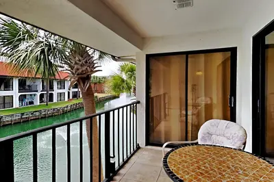 a balcony with a table and a chair and a palm tree at Edgewater Villa #2209 in Panama City Beach