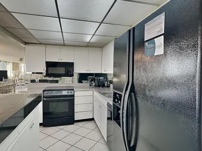 a kitchen with white cabinets and a stainless steel refrigerator at Edgewater Tower I #207 in Panama City Beach