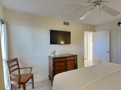 a bedroom with a bed and a chair and a tv at Edgewater Tower I 211 in Panama City Beach