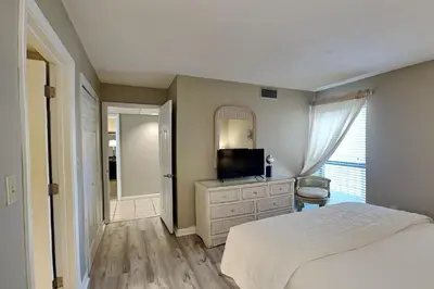 a bedroom with a bed and a tv and a mirror at Edgewater Tower I 406 in Panama City Beach