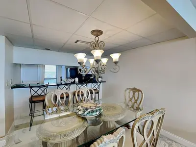 a dining room with a glass table and chairs at Edgewater Tower I 610 in Panama City Beach