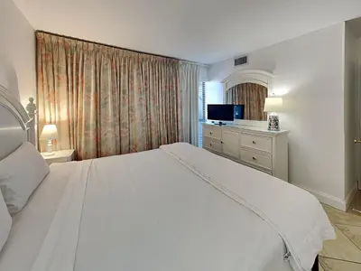 a bedroom with a large white bed and a television at Edgewater Tower I 802 in Panama City Beach