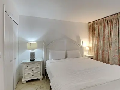 a bedroom with a white bed and a nightstand with a white bedspread at Edgewater Tower I 802 in Panama City Beach