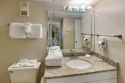 a bathroom with a sink and a toilet and a mirror at Edgewater Tower II 912 in Panama City Beach
