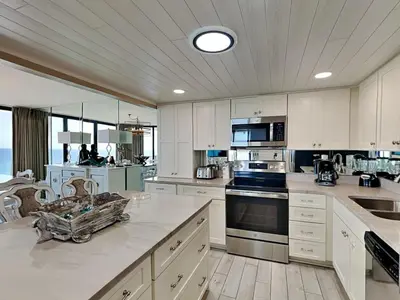 a large kitchen with white cabinets and stainless steel appliances at Edgewater Tower II 1001 in Panama City Beach