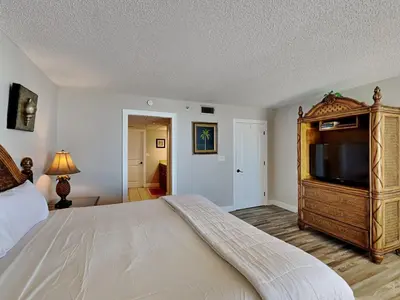 a bedroom with a large bed and a flat screen tv at Edgewater Tower III 114 in Panama City Beach