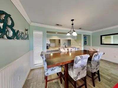 a dining room with a wooden table and white chairs at Edgewater Villa 1216 in Panama City Beach
