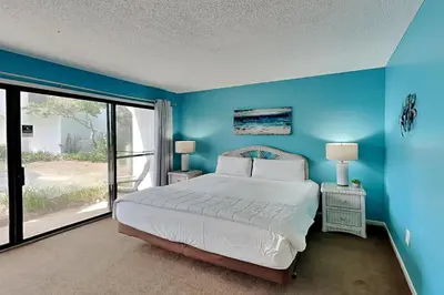 a blue bedroom with a bed and a large window at Edgewater Villa 1501 in Panama City Beach