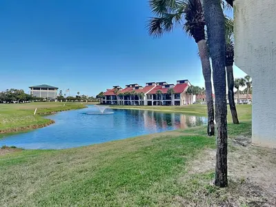 a palm tree next to a river with houses at Edgewater Villa 1501 in Panama City Beach