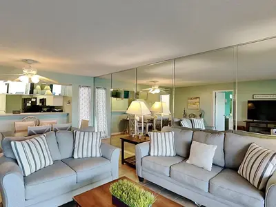 a living room with two couches and a large mirror at Edgewater Villa 1501 in Panama City Beach