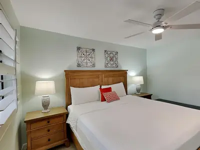 a bedroom with a white bed with two red pillows at Edgewater Villa #2505 in Panama City Beach