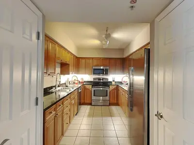 a kitchen with wooden cabinets and a stainless steel refrigerator at Emerald Beach #2535 in Panama City Beach