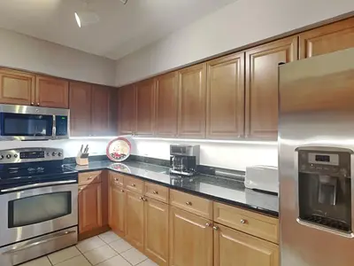 a kitchen with wooden cabinets and a stainless steel refrigerator at Emerald Beach #2535 in Panama City Beach