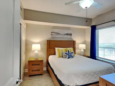 a bedroom with a bed with two lamps and a window at Grand Panama Beach Resort - The Grand #1304 in Panama City Beach