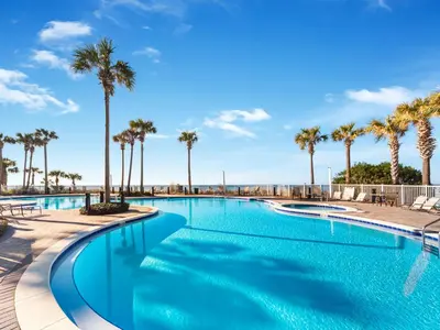 a swimming pool with palm trees in a resort at Grand Panama Beach Resort - The Grand #1304 in Panama City Beach