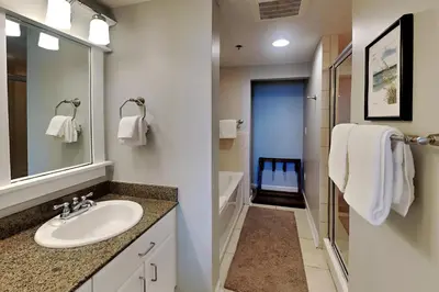 a bathroom with a sink and a mirror and a tub at Grand Panama Beach Resort - The Grand #403 in Panama City Beach