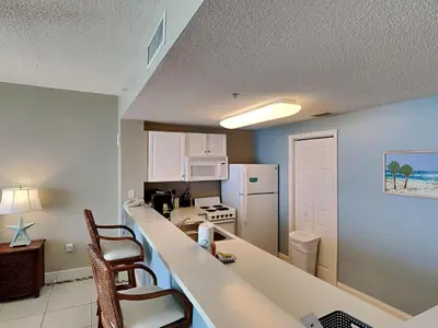 a kitchen with a counter and a kitchen with a refrigerator at Majestic Beach Towers I #1608 in Panama City Beach