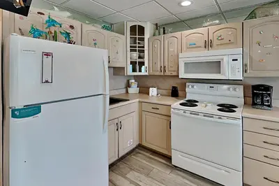 a kitchen with white appliances and wooden cabinets at Continental 319 in Panama City Beach