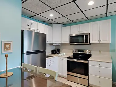 a kitchen with white cabinets and a stainless steel refrigerator at Continental 419 in Panama City Beach