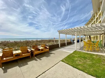 a patio with tables and chairs next to the beach at Continental 503 in Panama City Beach