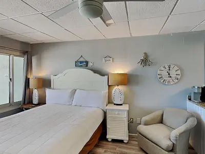 a bedroom with a bed and a chair and a clock at Continental Condominiums 3 in Panama City Beach