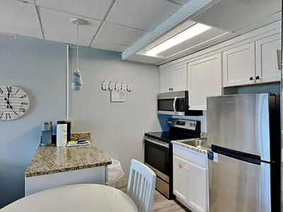 a kitchen with white cabinets and a stainless steel refrigerator at Continental Condominiums 3 in Panama City Beach