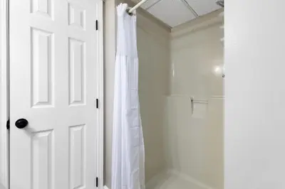 a bathroom with a shower and a white door at Edgewater Tower I 704 in Panama City Beach