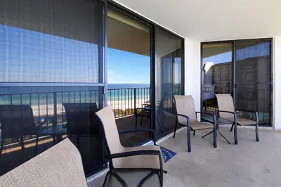 a balcony with chairs and a table with a view of the ocean at Edgewater Tower I 704 in Panama City Beach