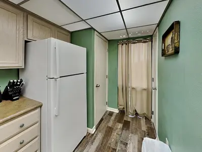 a kitchen with a white refrigerator and green walls at Edgewater Tower II #204 in Panama City Beach