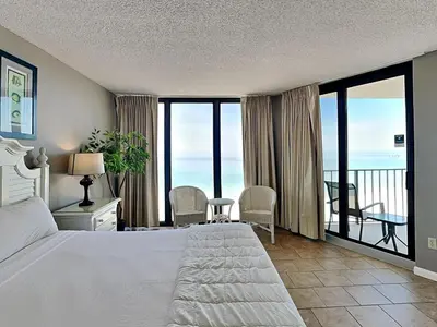 a bedroom with a bed and a balcony with the ocean at Edgewater Tower II 1004 in Panama City Beach