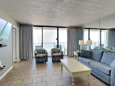 a living room with a blue couch and two chairs at Edgewater Tower II 1004 in Panama City Beach