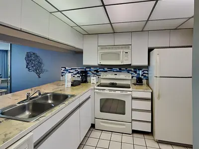 a kitchen with a sink and a stove and a microwave at Edgewater Tower II 1004 in Panama City Beach