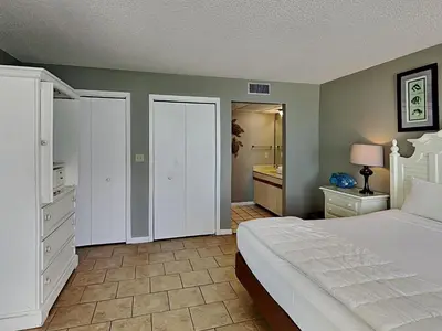 a bedroom with a white bed and a bathroom at Edgewater Tower II 1004 in Panama City Beach