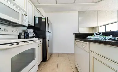 a kitchen with a refrigerator and a stove top oven at Edgewater Tower III #606 in Panama City Beach