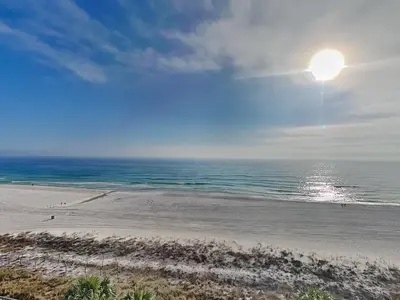 a beach with the sun shining on the ocean at Edgewater Tower III #606 in Panama City Beach