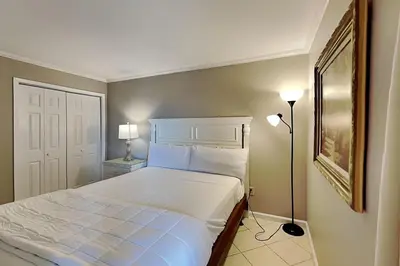 a bedroom with a white bed and a lamp at Edgewater Tower III #607 in Panama City Beach