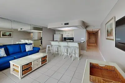 a living room with a blue couch and a kitchen at Edgewater Tower III #607 in Panama City Beach