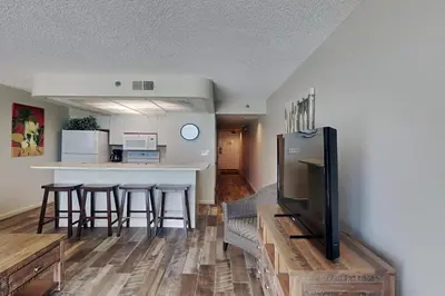 a living room with a kitchen and a bar with stools at Edgewater Tower III #609 in Panama City Beach