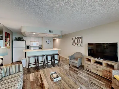 a living room with a kitchen and a bar at Edgewater Tower III #609 in Panama City Beach