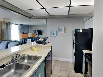 a kitchen with a sink and a black refrigerator at Edgewater Tower III 707 in Panama City Beach