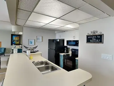 a kitchen with a sink and a black refrigerator at Edgewater Tower III 707 in Panama City Beach