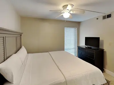 a bedroom with a bed with a ceiling fan and a television at Edgewater Tower III 707 in Panama City Beach