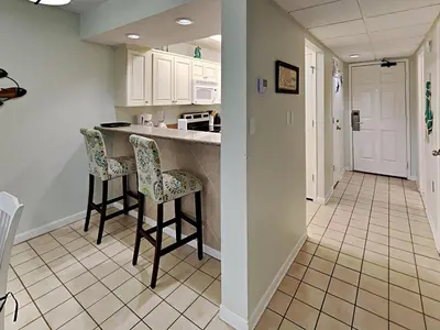 a kitchen with two bar stools and white cabinets at Edgewater Villa #704 in Panama City Beach