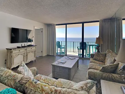 a living room with a couch and a television and a balcony at Edgewater Tower III #804 in Panama City Beach