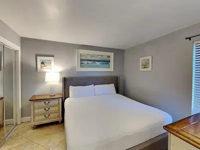 a bedroom with a bed and a table and a window at Edgewater Tower III 907 in Panama City Beach