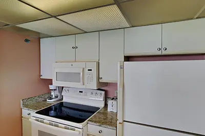 a kitchen with white cabinets and a stove and microwave at Edgewater Tower III 1106 in Panama City Beach