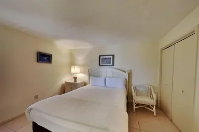 a bedroom with a large white bed and a chair at Edgewater Tower III 1108 in Panama City Beach