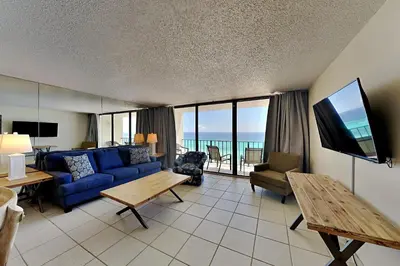 a living room with a blue couch and a tv at Edgewater Tower III 1108 in Panama City Beach