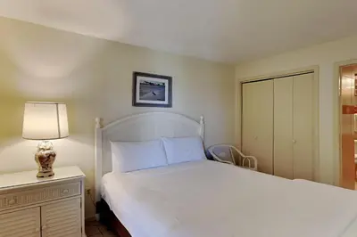 a bedroom with a white bed and a lamp on a night stand at Edgewater Tower III 1108 in Panama City Beach