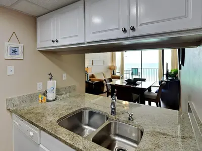 a kitchen with a sink and a living room at Edgewater Leeward #605 in Panama City Beach
